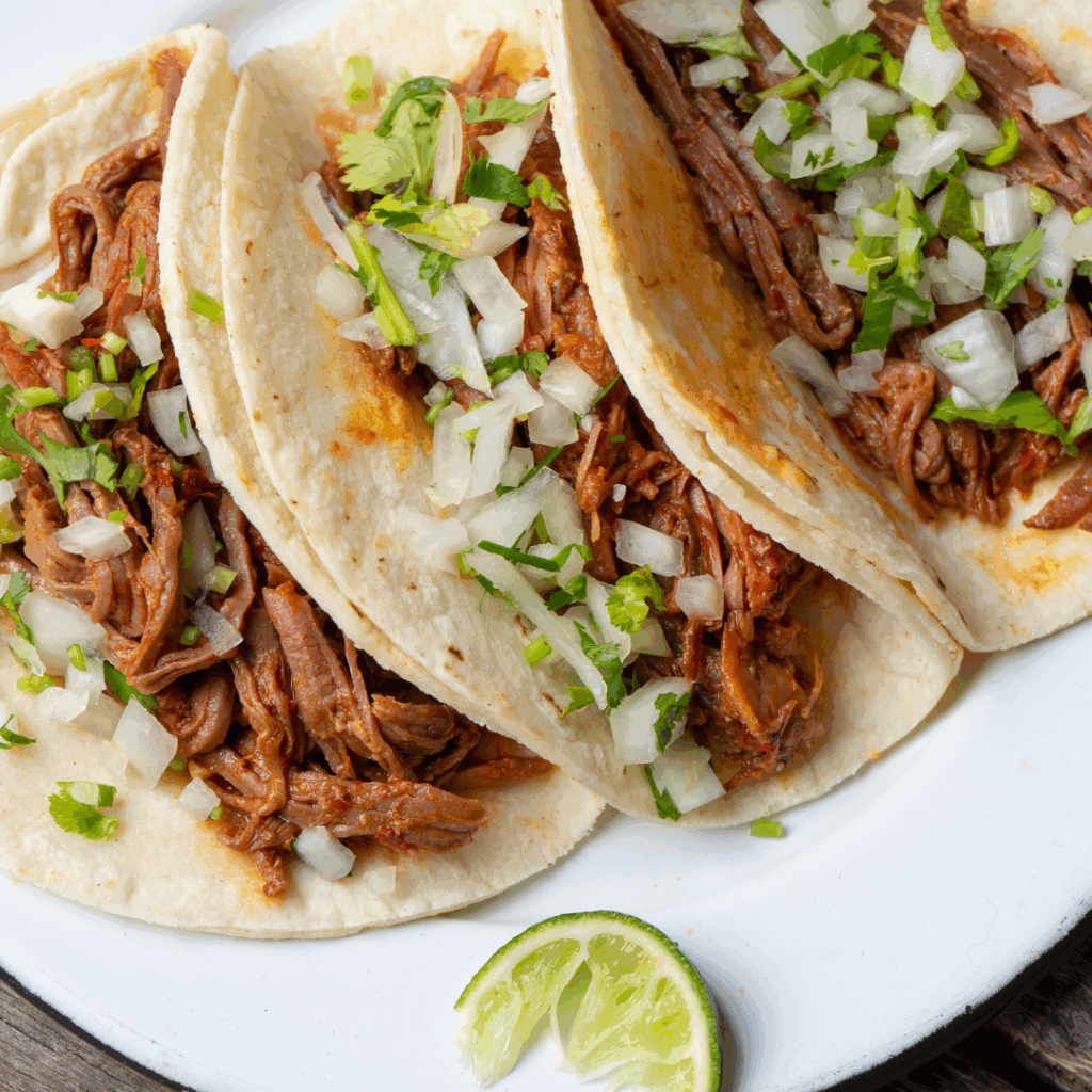 Plate of street-style tacos served with fresh toppings at Beverly Beach Garden Taco Tuesday in Pacific Beach.